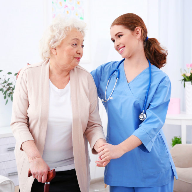 caregiver and elderly woman smiling to each other