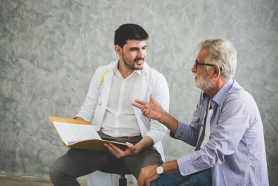 senior man wearing eyeglasses talking with his speech therapist