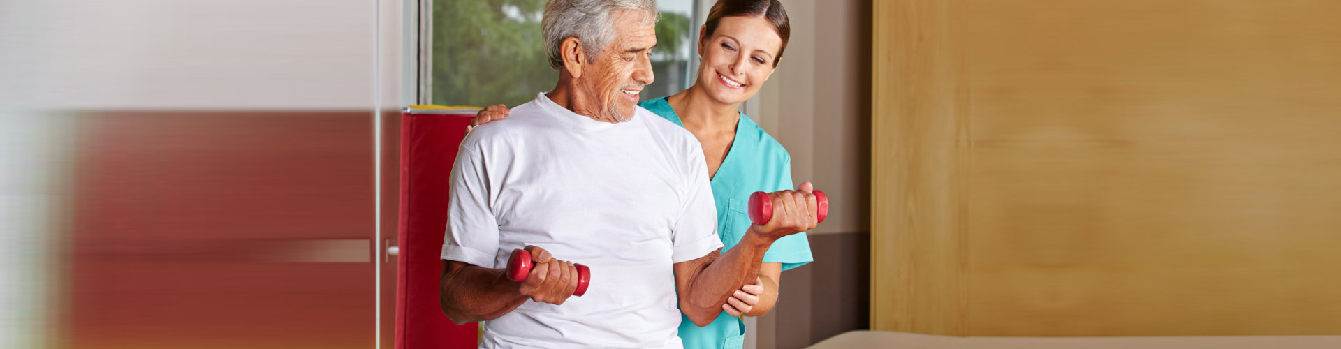physiotherapist assisting senior man exercising with dumbbells
