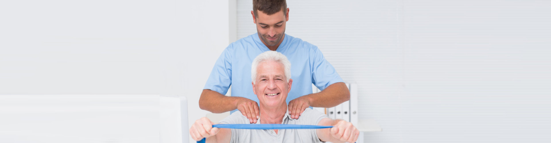male physical therapist assisting senior man in exercising with resistance band