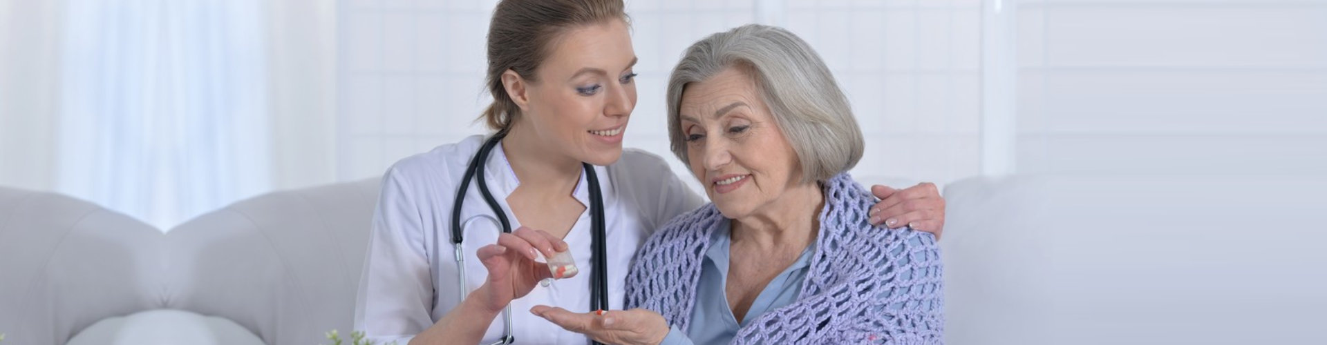 caregiver giving medicine to senior woman